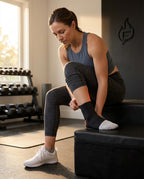Woman in a gym pulling the black ankle sleeve onto her foot before a run