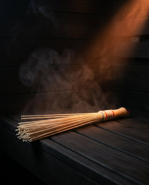 Bamboo massage roller resting on a dark sauna bench amid steam