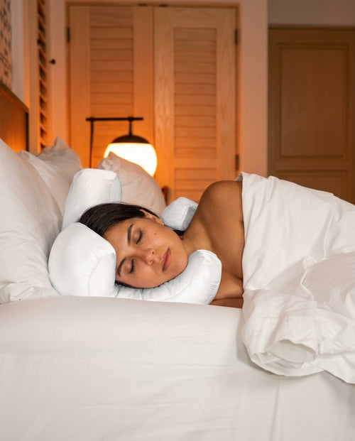 Woman side-sleeping with cheek cradled in the white support pillow in dim bedroom