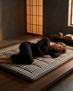 Woman sleeping on her side on a checkered floor mattress in a Japanese-style room