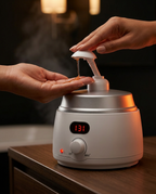 Hands pumping warm oil from the dispenser in a dim spa bathroom