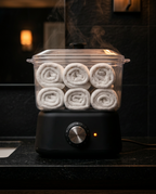 Towel warmer steaming on a dark spa bathroom counter with warm light