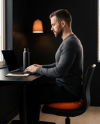 Man working at a desk using the orange balance disc as an active-sitting seat