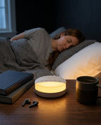 Glowing sleep machine on a bedside table as a woman sleeps behind it