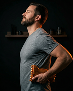 Bearded man using the wooden massage roller for self-massage on his lower back
