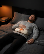 Man on a bed relaxing with the waist massager belt across his midsection