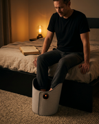 Man on a bed at night resting his feet inside the heated leg warmer