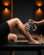 Therapist rolling the heated massage gun over a woman's calf for recovery