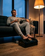 Man relaxing on a couch at night using the foot massager cushion