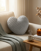 Heart-shaped weighted cushion resting on a cream armchair with a candle