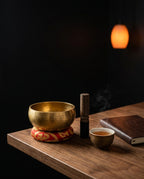 Singing bowl on a red cushion on a wood desk with striker and tea cup