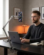Man at a desk with the phone arm clamped on, holding his phone during a video call