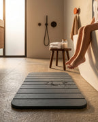 Grey stone bath mat on a bathroom floor beside a bathtub