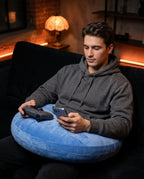 Man gaming on a sofa, controller resting on the blue lap support pillow
