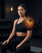 Woman in a dark gym wearing the heated shoulder brace after a workout