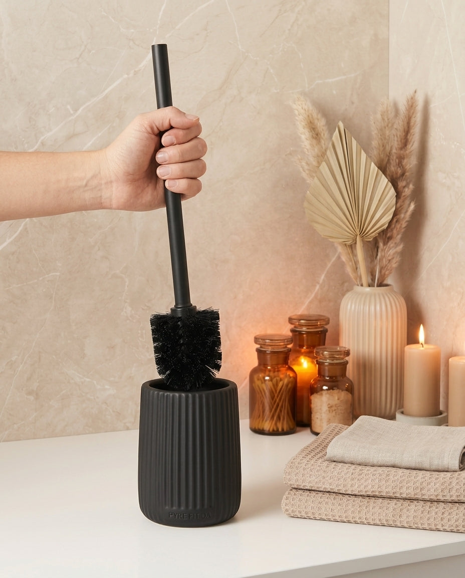 Hand lifting the black brush from the ribbed ceramic holder in a bathroom