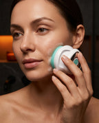 Woman cleansing her face with the detachable handheld brush head and green bristles