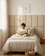 Child reading on a bed against beige upholstered wall panels in a kids room