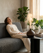 Woman relaxing on a sofa in a plant-filled living room with the diffuser