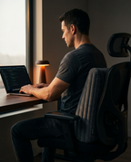 Man working at a desk with the inflatable wedge pillow as lumbar support on his chair