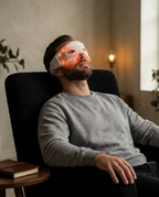 Man reclining on a chair wearing the red light LED eye mask