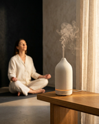 White ceramic essential oil diffuser misting in a calm meditation corner