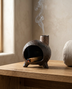 Ritual burner on a wood table releasing a thin smoke trail in a meditation corner