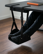 Feet propped in the foot hammock hung under a home office desk