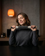 Woman at a desk resting the massage stick against her neck, eyes closed