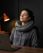 Woman power napping at her desk wearing the grey travel neck pillow