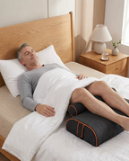 Older man resting in bed with legs elevated on the black recovery wedge cushion