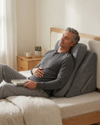 Man resting and recovering propped upright on the gray sleep wedge lounger in bed
