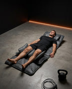 Man lying on the massage mat on a gym floor after a workout, kettlebell near