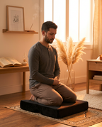 Man kneeling in prayer on the black memory foam cushion by a window