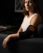 Woman relaxing on a couch wearing the glowing heated elbow sleeve