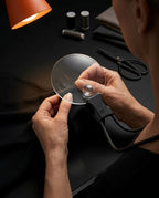 Person threading a needle through the neck magnifier lens while sewing