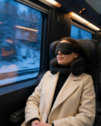 Woman dozing on a snowy train commute in the travel neck pillow and mask