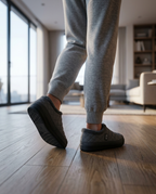 Person walking indoors on wood floor wearing the grey heated slippers