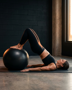 Woman doing a core hip bridge with legs on the stability ball in a gym