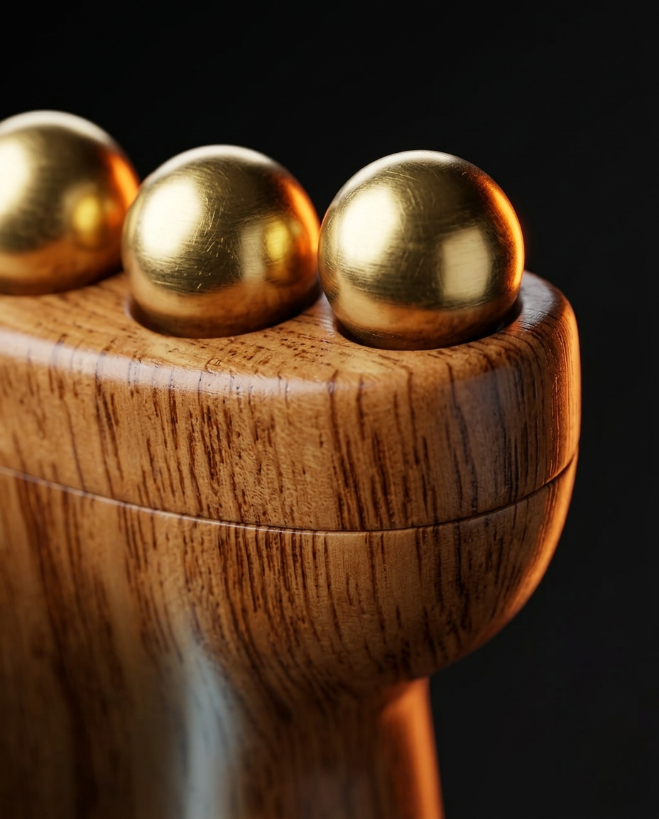 Macro of polished brass massage beads set into the wooden roller's grained head
