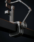Macro of the phone arm's C-clamp and knurled knob gripping a desk edge