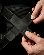 Hands tightening the dual cross-pull straps of the lower back support belt