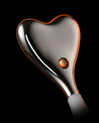 Macro of polished heart-shaped stainless steel eye massager head with warm reflections