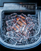 Macro inside the ice maker basket full of fresh clear bullet ice cubes