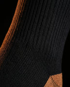 Macro of the ribbed black knit and copper accent of the compression sock
