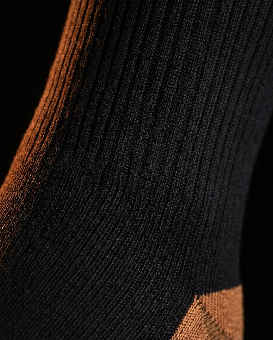 Macro of the ribbed black knit and copper accent of the compression sock