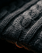 Macro close-up of the charcoal cable-knit wrap fabric with orange accent thread