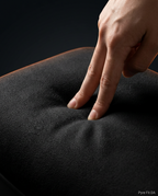 Finger pressing into the soft memory foam of the black foot cushion, macro