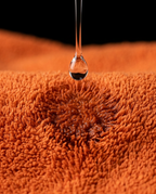 Water droplet absorbing into the orange microfiber yoga towel weave