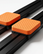 Macro of the orange textured kneepads sliding on the black pilates rails